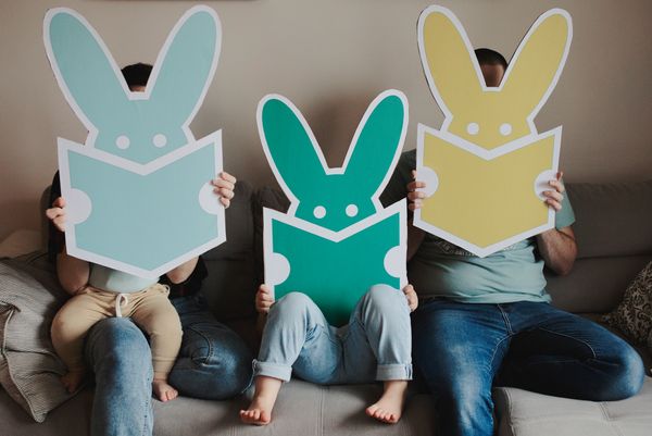 Rodzina z dziećmi trzyma plansze z zajączkami - logo firmy.